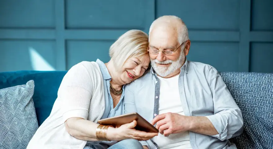 Uśmiechnięta para seniorów przegląda tablet. Szukają informacji: operacja zaćmy NFZ gdzie najszybciej, by odzyskać jasność widzenia.